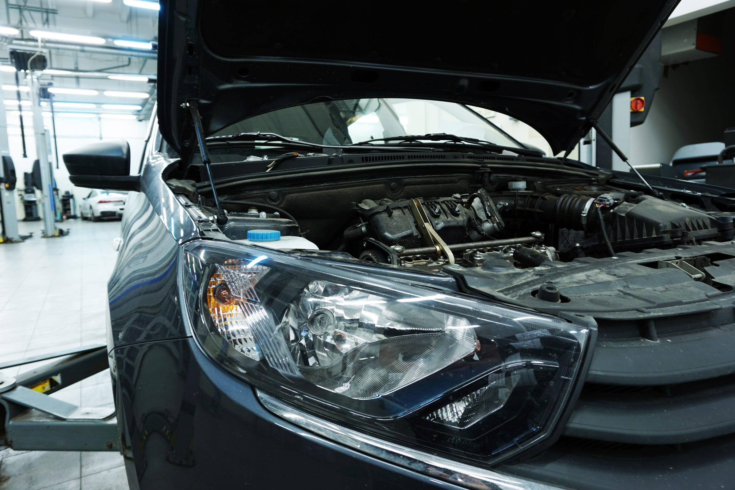 A modern car in service on a lift with an open hood.