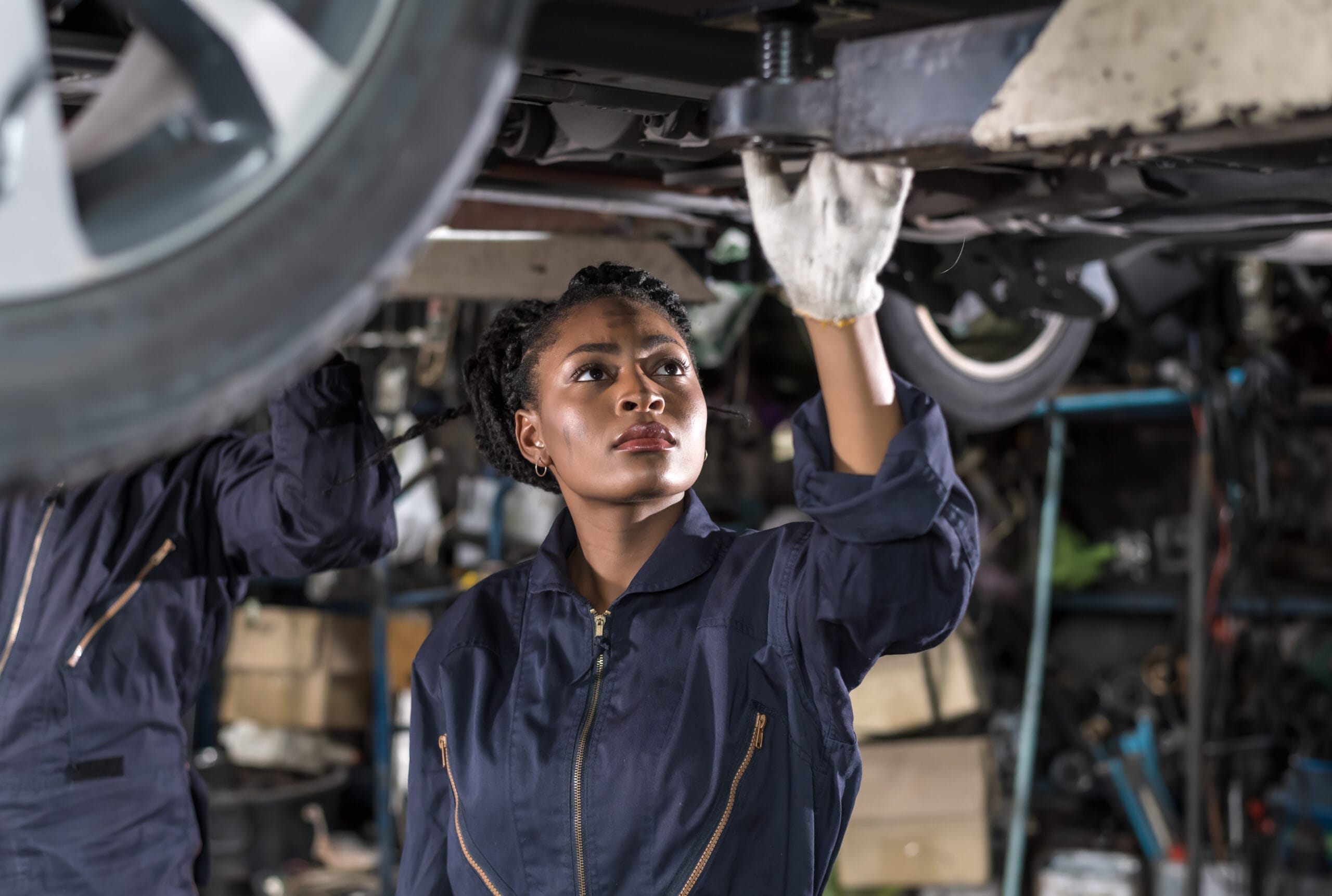 Black auto mechanic woman fixing car in auto repair garage