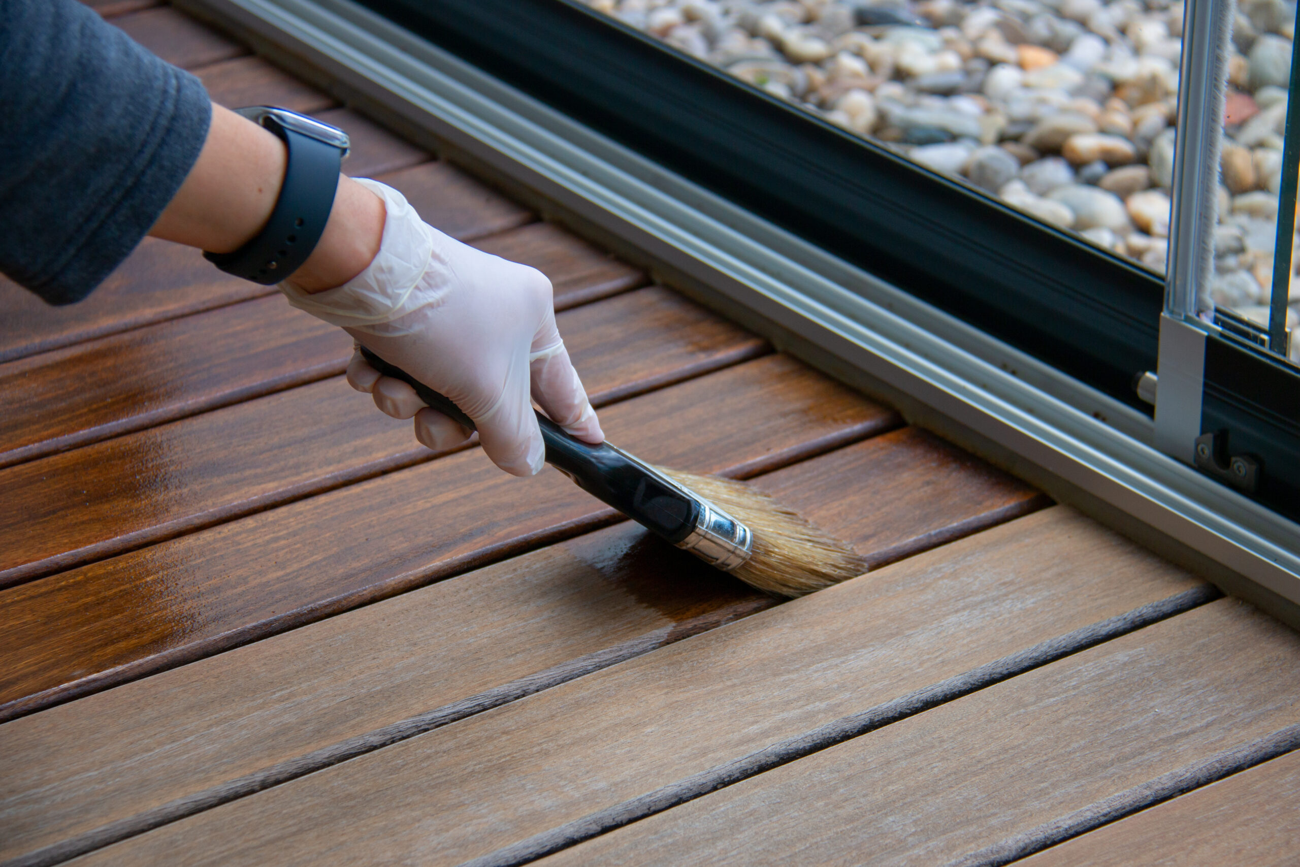 Image of someone applying shingle oil to decking boards