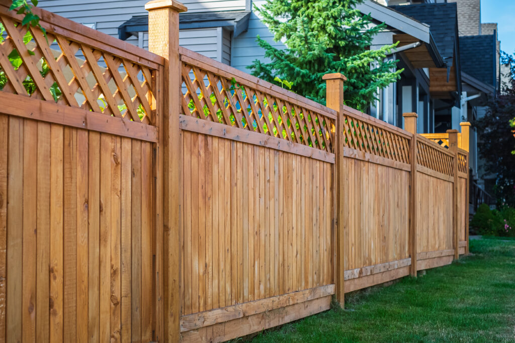 Wood fence in a backyard with a grass lawn around it