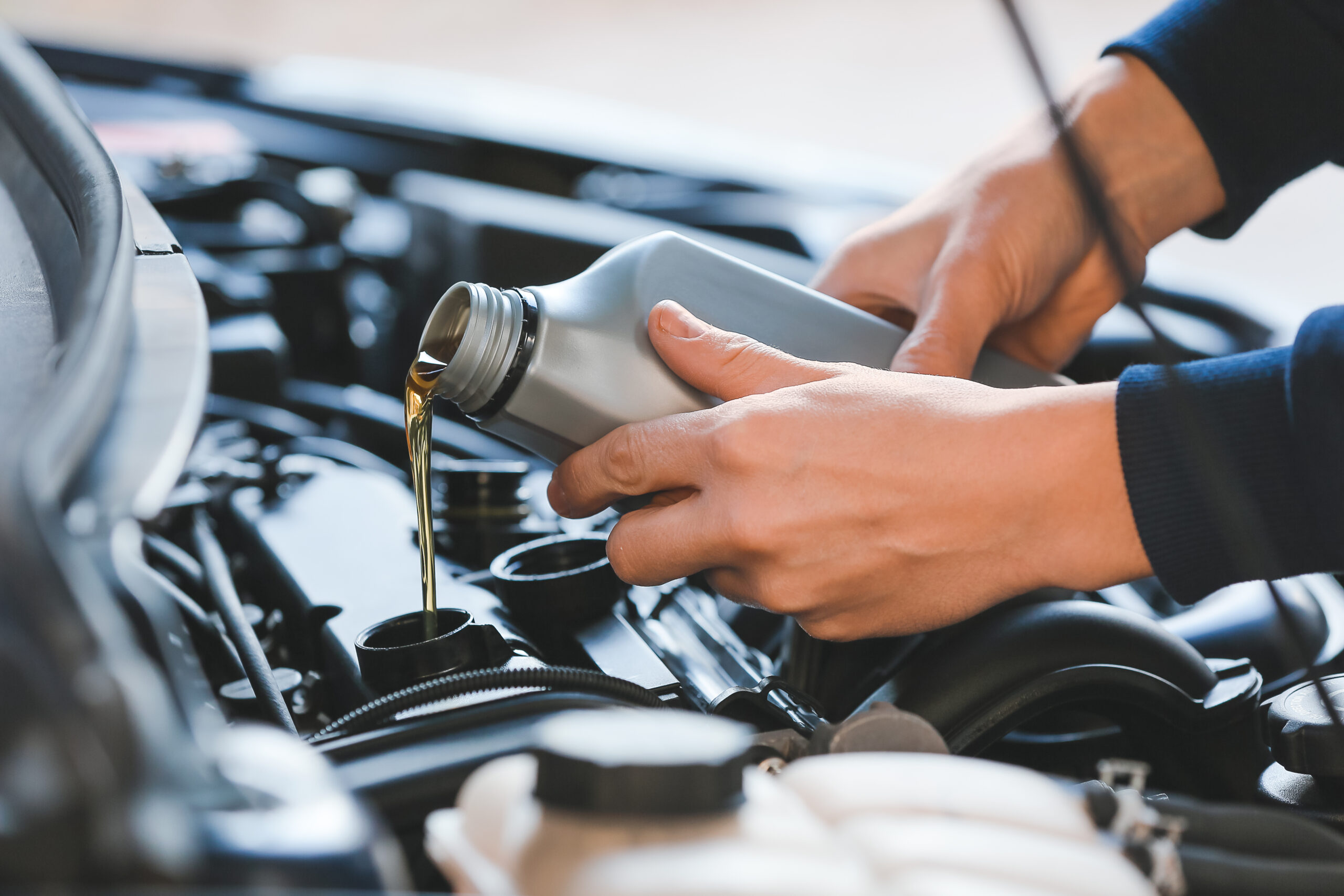 Mechanic refilling car oil in service center