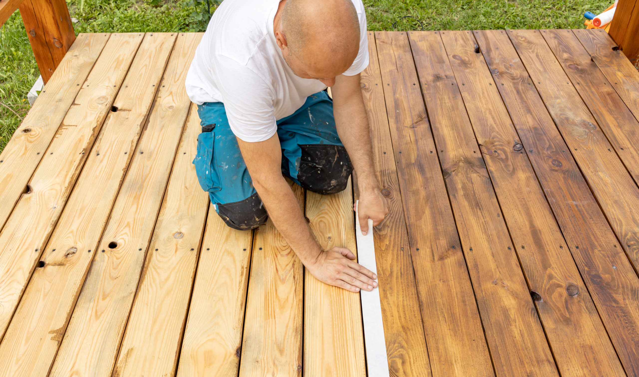 Man applying tape to wood deck with before and after of wood sealer