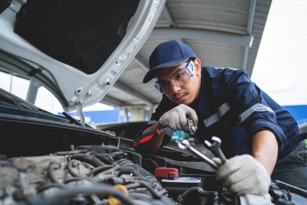 Mechanic working on car with front hood open