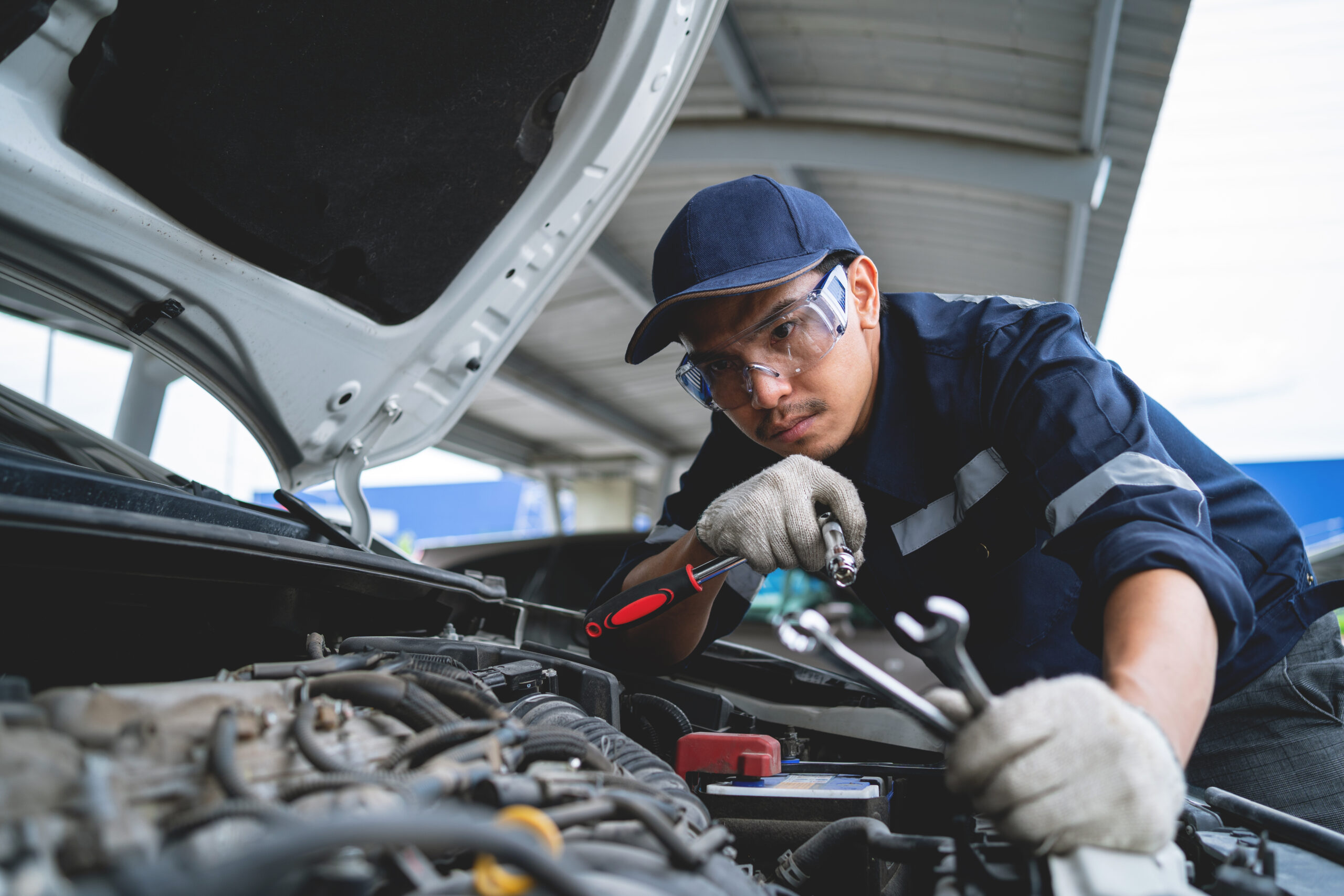 Mechanic working on car with front hood open